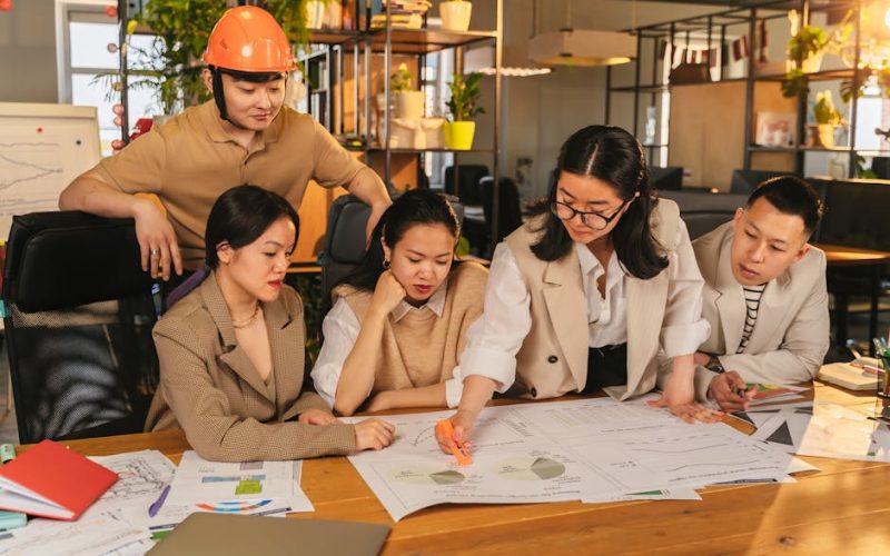 A diverse team of professionals working together on architectural plans in a modern office setting.